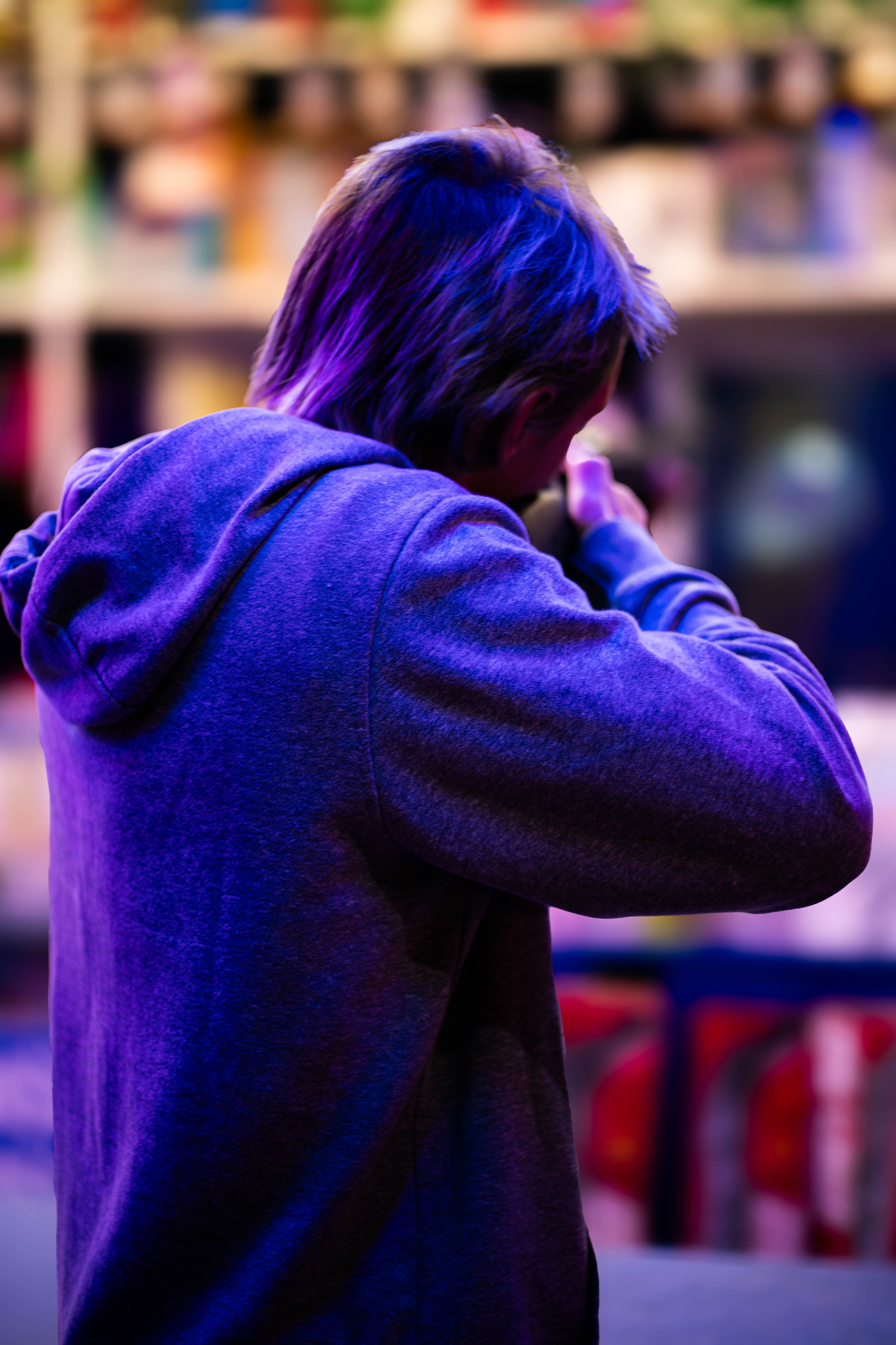 Photo d'un jeune homme de dos visant avec un fusil à air comprimé dans une fête foraine